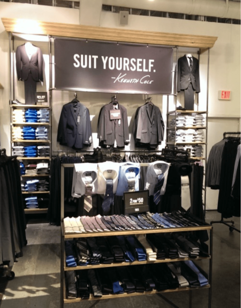Men's formal suits and ties hanging under a board that says 'Suit yourself by Kenneth Cole'.